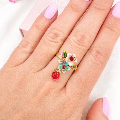 Anillo ajustable con fresa esmaltada y flores de colores llevado en la mano de una modelo.