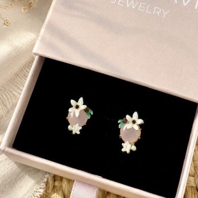Pendientes de flores blancas con piedra rosa sobre caja regalo AdoraVi