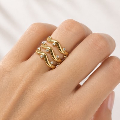Anillo dorado ajustable con circonitas puesto en mano femenina mostrando diseño ondulado moderno