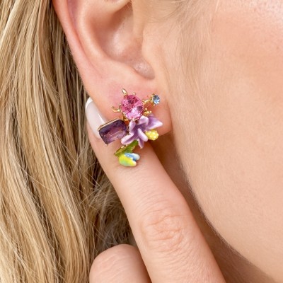 Pendientes florales con cristales morados y flores esmaltadas multicolor puestos en la oreja de una modelo.