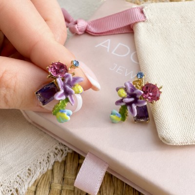 Pendientes románticos de flores esmaltadas y cristal morado sobre caja rosa de joyería AdoraVi.