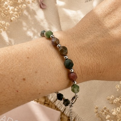 Pulsera de piedras naturales multicolor puesta en la muñeca de una mujer