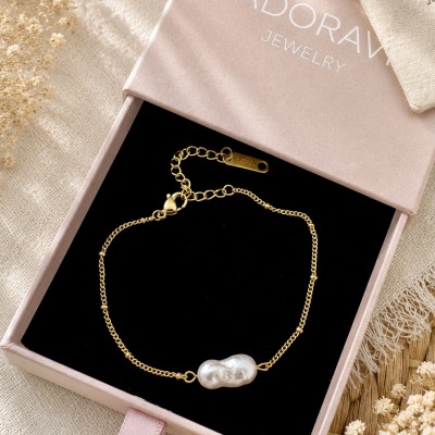Pulsera de acero inoxidable bañada en oro con perla barroca natural presentada en caja AdoraVi Jewelry.