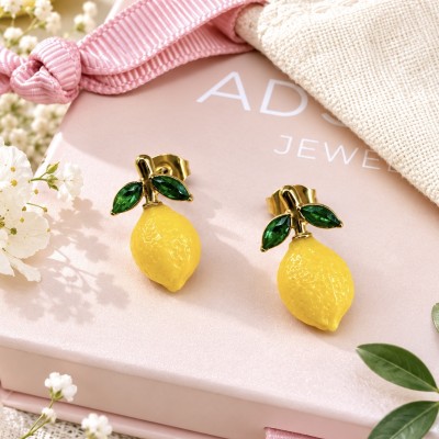 Pendientes de limón sobre caja de regalo AdoraVi con acabado dorado y hojas verdes
