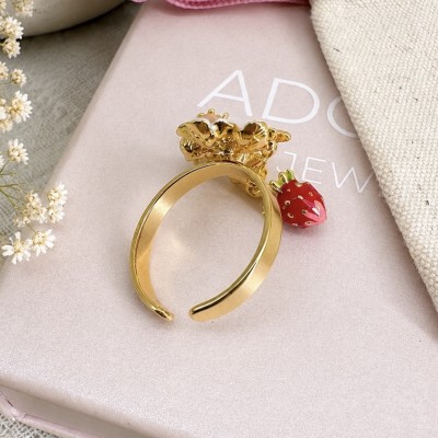 Vista lateral del anillo ajustable con acabado dorado y decoración de fresa esmaltada.
