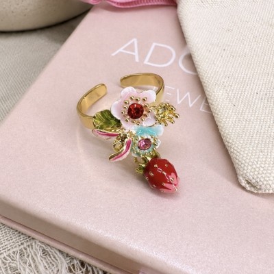Detalle del anillo romántico con fresa y flores esmaltadas sobre caja rosa de joyería.