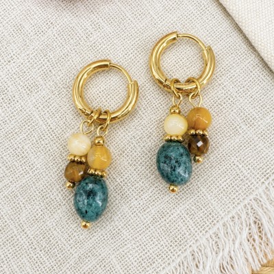 Pendientes artesanales de acero inoxidable dorado con piedras naturales sobre fondo de lino.