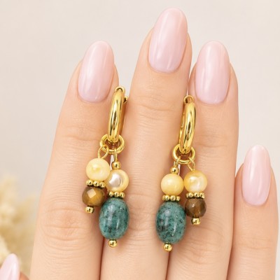 Pendientes de acero dorado con piedras naturales ojo de tigre y jaspe africano sobre mano.