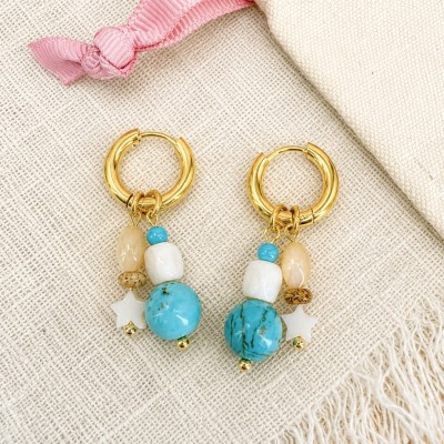 Pendientes hechos a mano con turquesa, nácar y concha natural sobre fondo de lino.