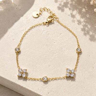 Pulsera dorada con circonitas de alta calidad sobre fondo de piedra clara.