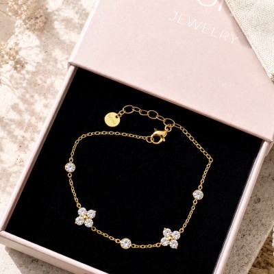Pulsera de acero inoxidable con baño de oro y flores de circonitas en caja de regalo.