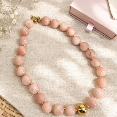 Collar rosa de cuentas con acero inoxidable chapado en oro PVD sobre fondo claro.