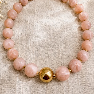 Collar rosa ajustable con cuentas marmoleadas y detalle dorado central.