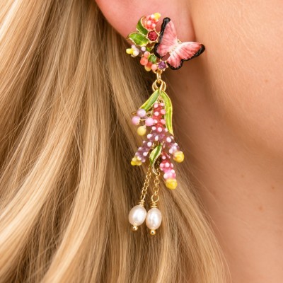 Pendientes largos de mariposa y flores puestos en oreja modelo con diseño floral romántico